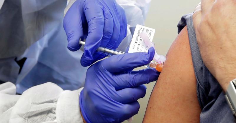 A healthcare professional wearing blue gloves expertly administers a COVID-19 vaccine injection, contributing to vital treatments in the fight against the virus.