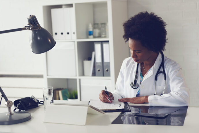 young african american female doctor writing at desk