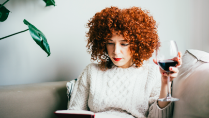 woman reading book drinking wine