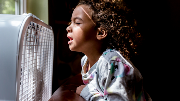 child in front of fan