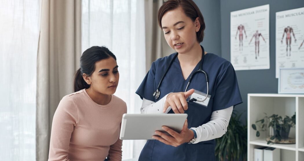 physician using tablet to administer a survey to a patient about their satisfaction with their treatment